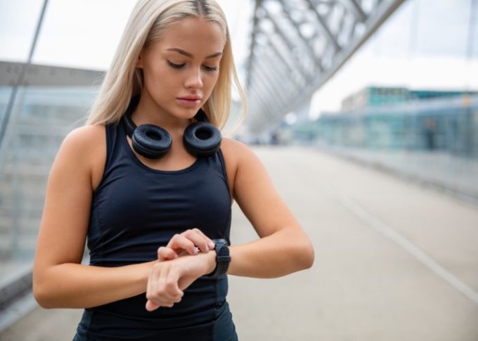Biegająca kobieta sprawdza tętno na smartwatchu z czujnikiem tętna
