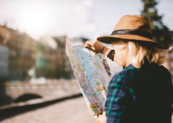 Kobieta sprawdza trasę na tradycyjnej mapie turystycznej