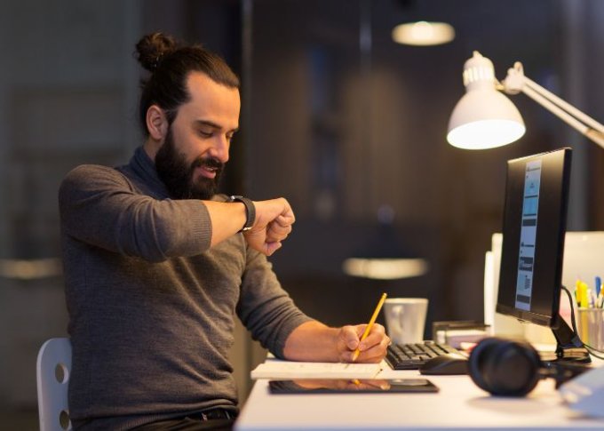 Mężczyzna pracujący przy biurku rozmawia przy pomocy swojego smartwatcha
