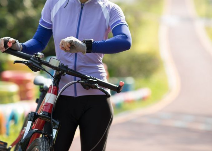 Kobieta z zegarkiem multisportowym podczas treningu rowerowego