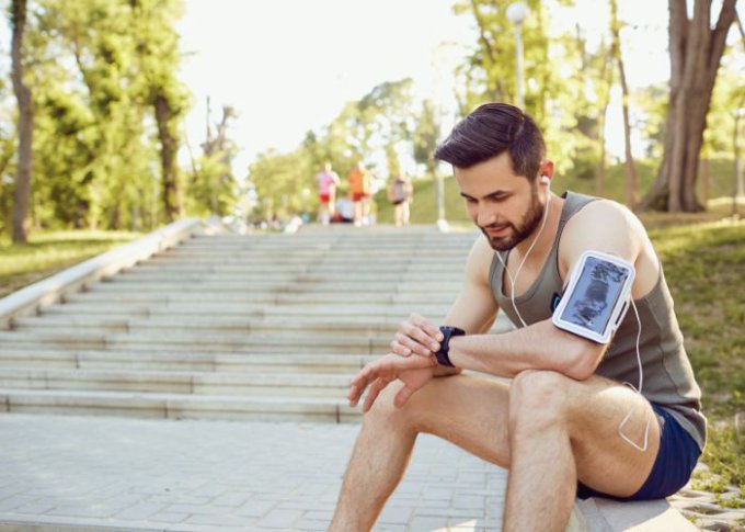 Mężczyzna uprawiający jogging w trakcie odpoczynku sprawdza swoje tętno na smartwatchu